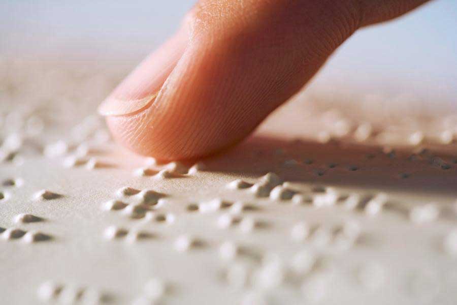 Image of braille with a finger reading it